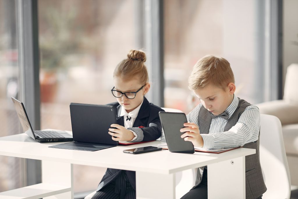 two blonde children dressed as adults working on laptops